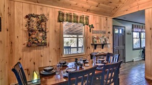 A wooden interior with a dining table set for four, a window with a view, and a door leading outside. - 'Nature's Retreat' w/ Hot Tub: 7 Mi to Bryson City (Whittier)