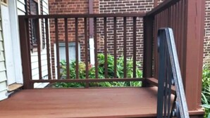 Eine Holztreppe mit Metallgeländer, das zu einer Veranda führt.