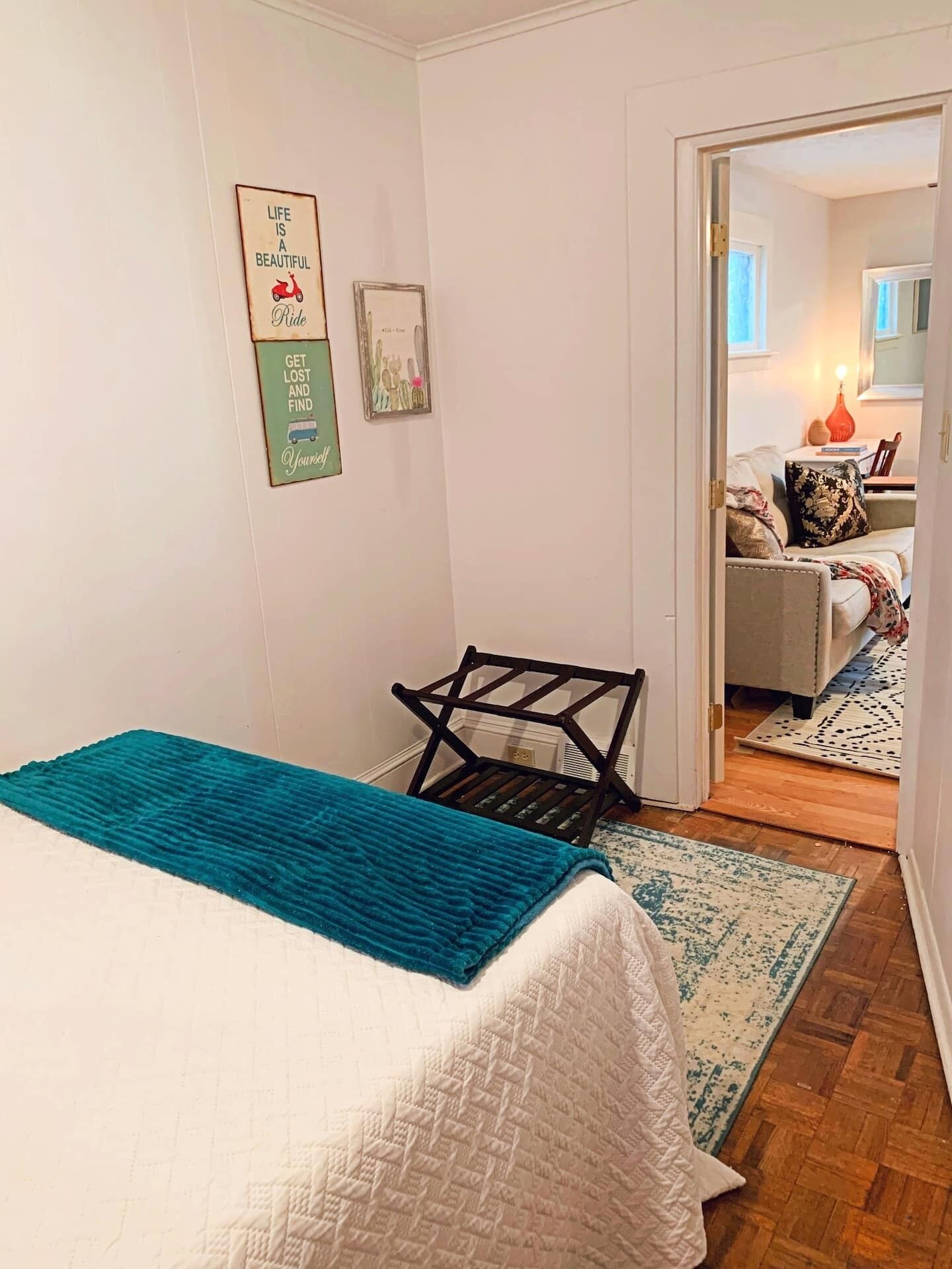 Ein Schlafzimmer mit Bett, Stuhl, einer Tür zu einem anderen Raum und einer Wand mit motivierenden Postern.