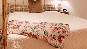 Ein Himmelbett mit floralem Bettbezug und einem schlichten Kopfkissen.