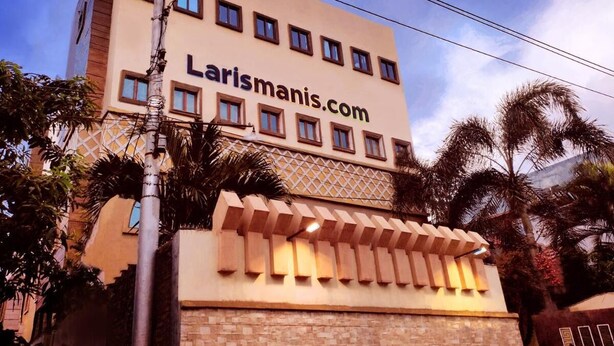 A hotel with a modern facade, multiple windows, and a prominent website address. - Hotel Syariah Larismanis (Semarang)