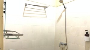 A small bathroom with a white sink, a shower, and a towel rack. - Hotel Syariah Larismanis (Semarang)