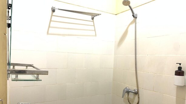 A small bathroom with a white sink, a shower, and a towel rack.