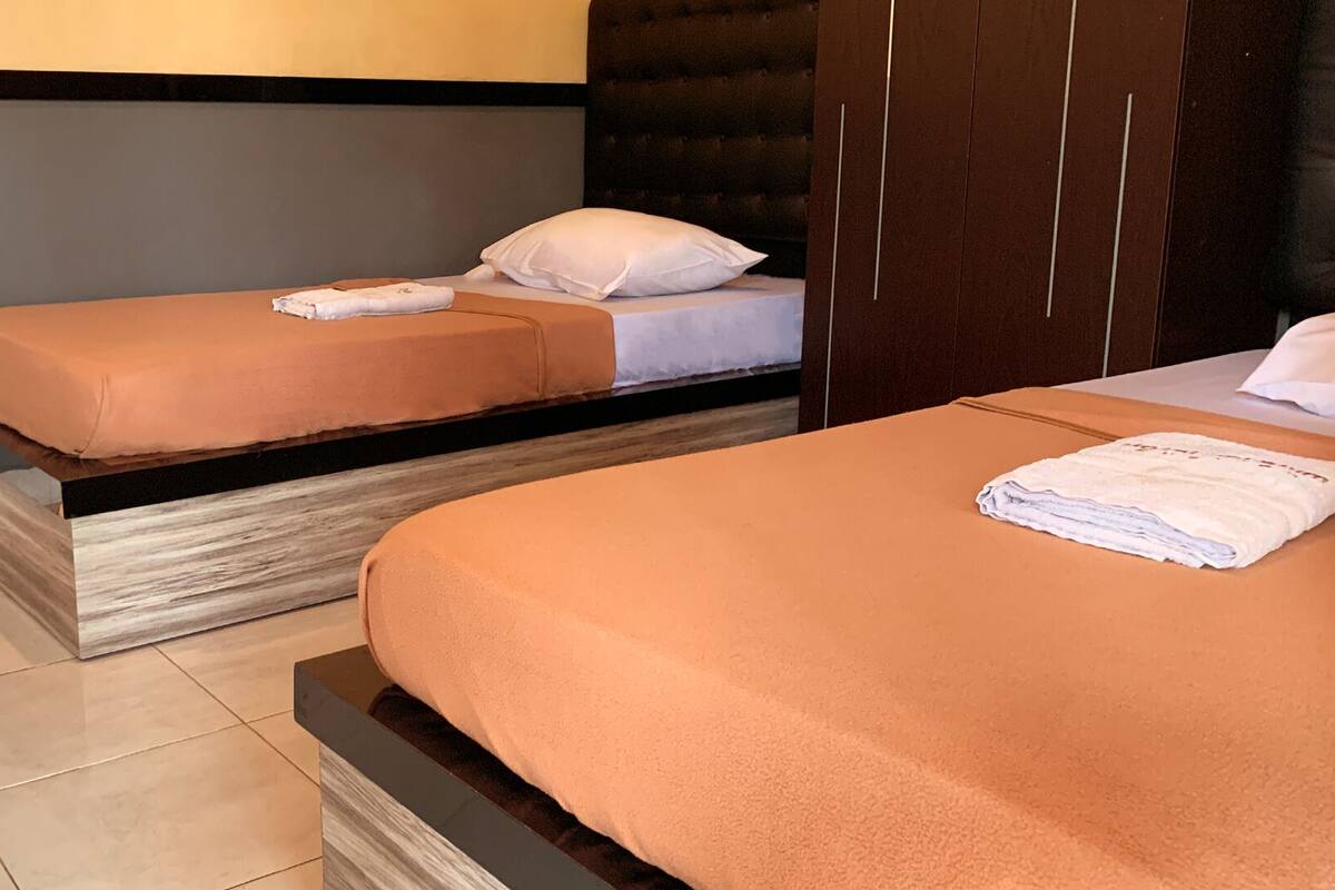Two single beds with orange bedding, a wooden headboard, and a grey wall.