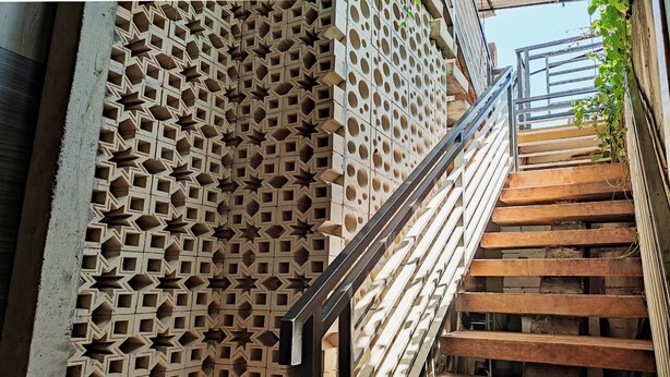 A staircase with a geometric patterned wall on one side and a metal railing.