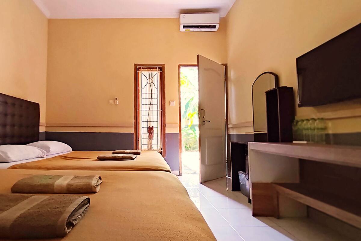 A hotel room with a large bed, a TV, and a bathroom visible through an open door.