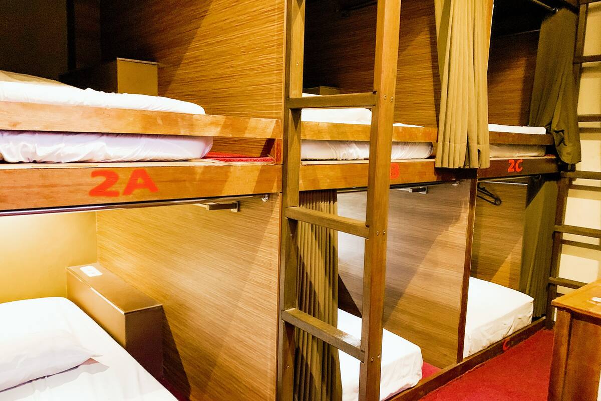 A dormitory room with bunk beds, wooden walls, and a red carpet.