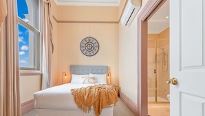 A bedroom with a bed, a wall clock, and a bathroom visible through an open door. - Clocktower Suites (Echuca)