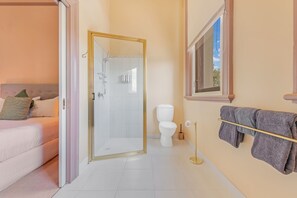 A bathroom with a glass-enclosed shower, a toilet, and a towel rack. - Clocktower Suites (Echuca)