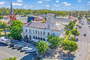 A historic building with a clock tower, surrounded by a parking lot and a street. - Clocktower Suites (Echuca)