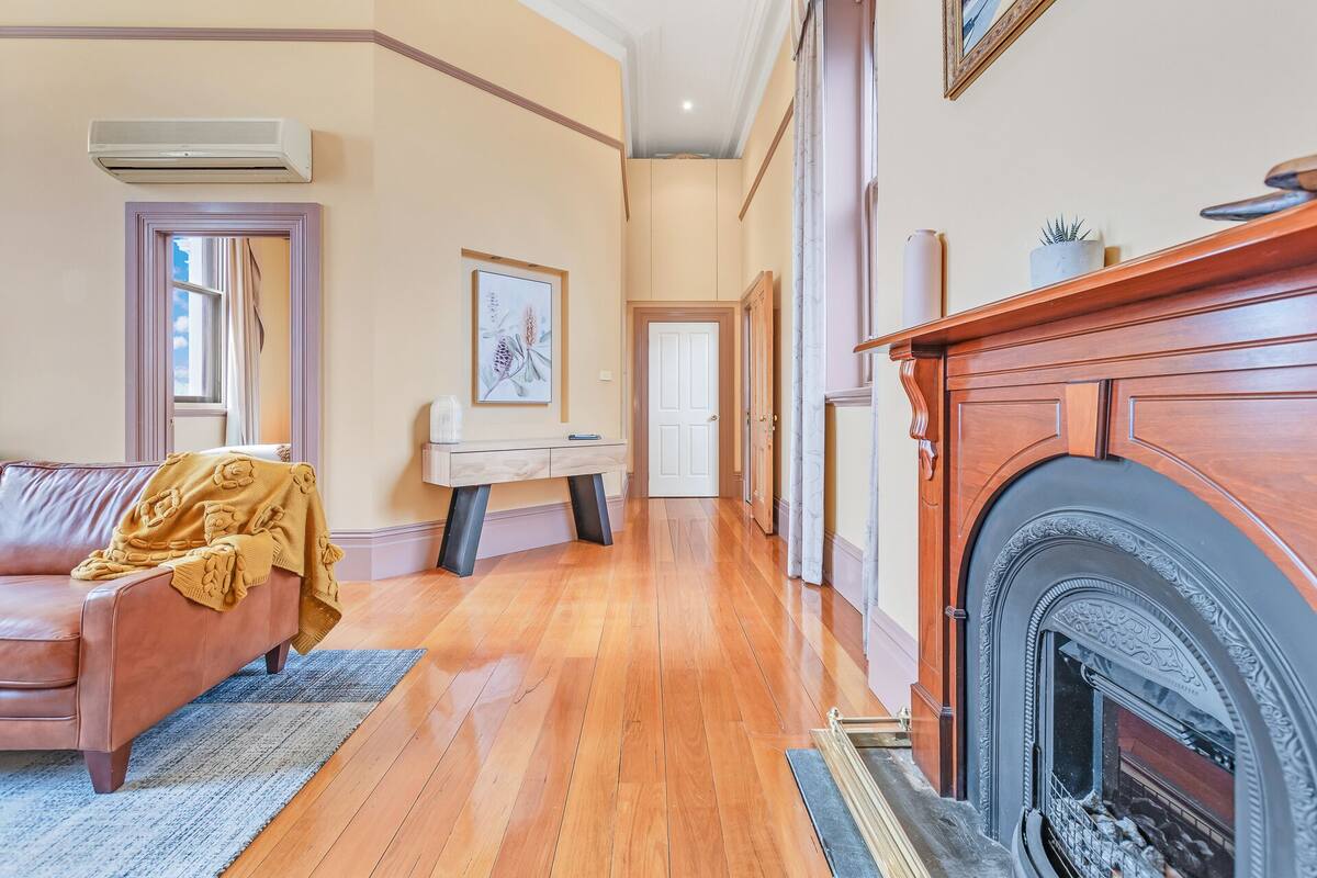 A spacious living room with a fireplace, a sofa, and a console table with a vase.
