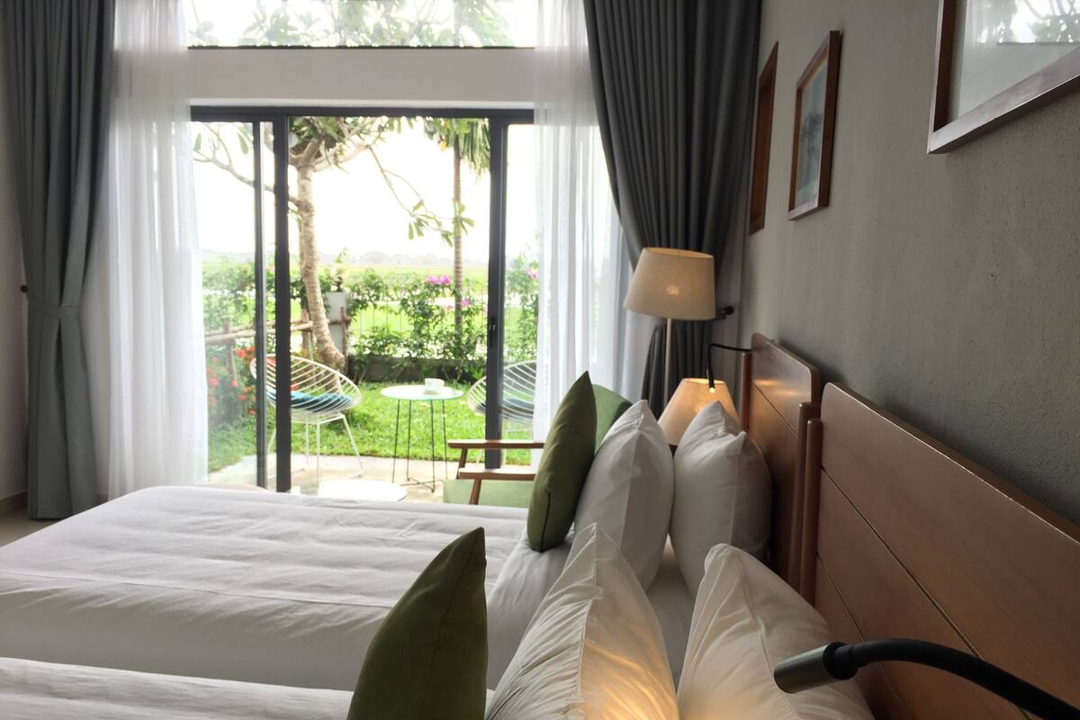 Ein Hotelzimmer mit Bett, Kissen, einer Lampe und Blick ins Freie.