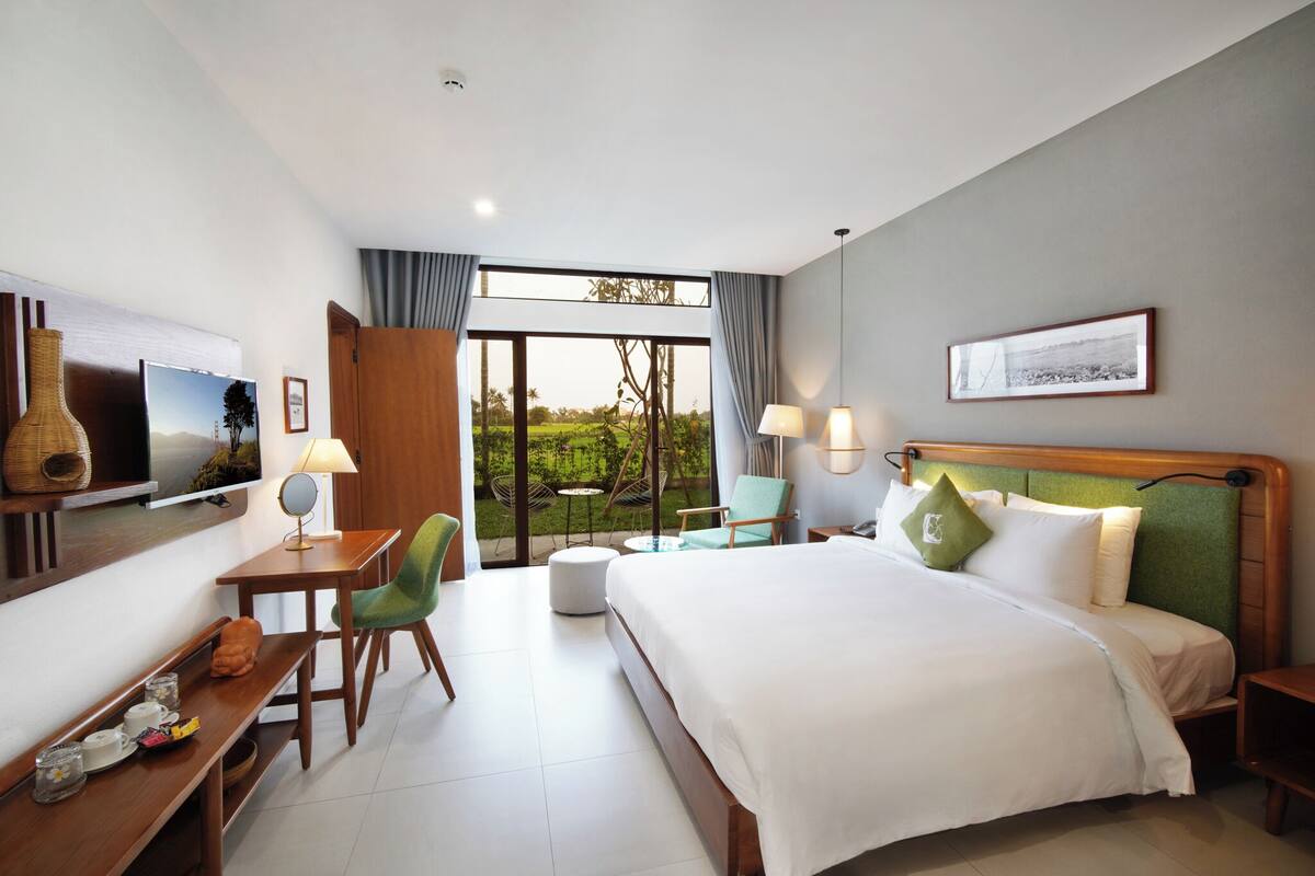 Ein Hotelzimmer mit Bett, Schreibtisch mit Stuhl, Fernseher, Fenster mit Blick und einer Lampe.