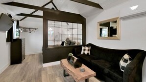A modern living room with a dark brown sofa, a wooden coffee table, and a large window.