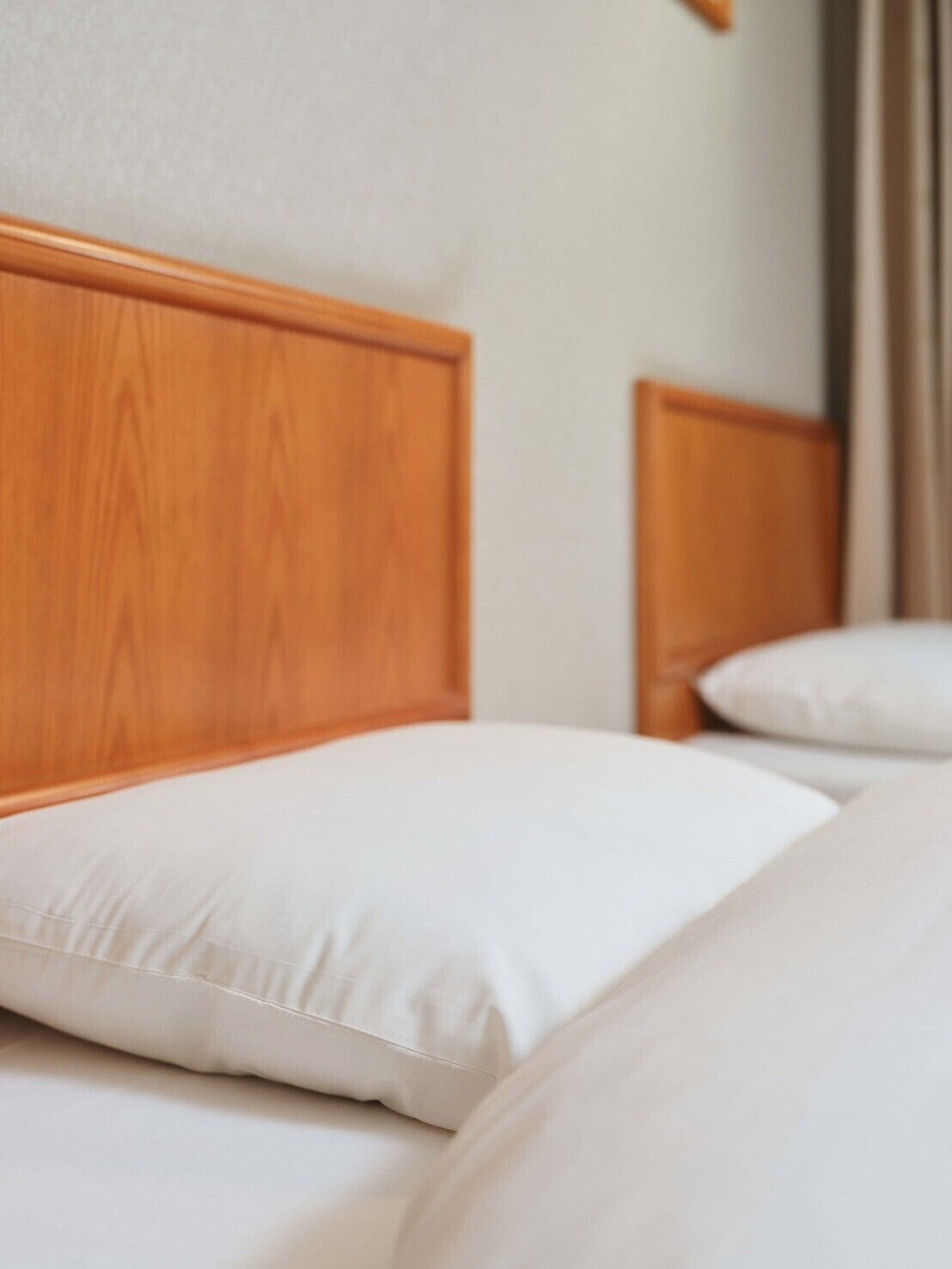 A hotel room with a wooden headboard and white bedding.