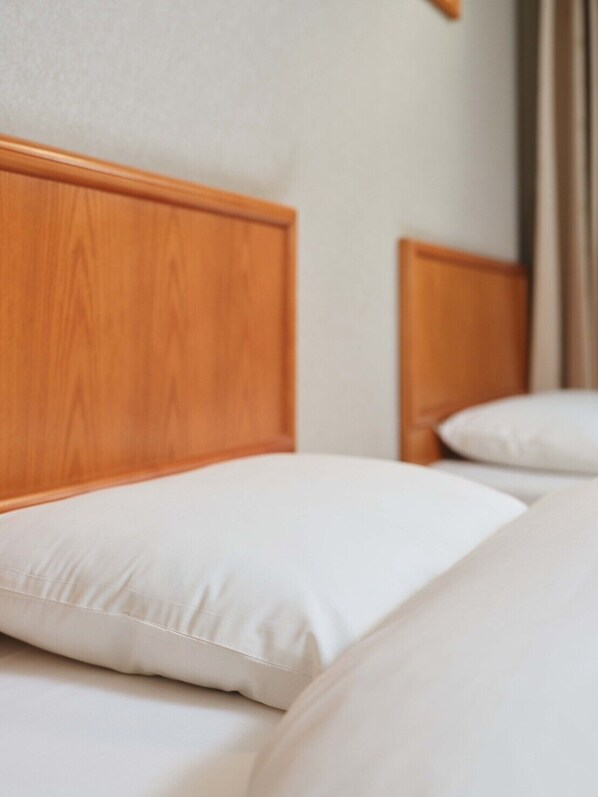 A hotel room with a wooden headboard and white bedding. - Kinsa Holiday Hotel (Jinsha)