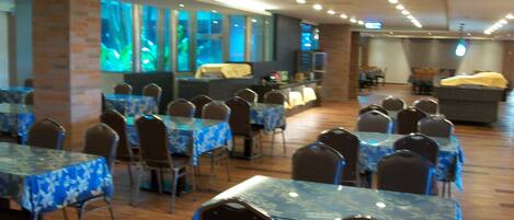 A dining area with tables covered in blue floral tablecloths, arranged in rows with chairs.