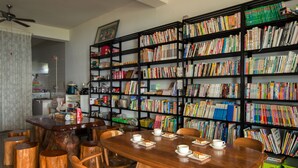 A library with a wooden table and chairs, surrounded by bookshelves filled with books. - Pu Su Bed and Breakfast (Lugu)