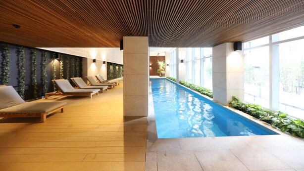 A modern indoor swimming pool with lounge chairs and a wooden ceiling. - Melbourne CBD 2BD! - Experience Rose Lane! (Melbourne)