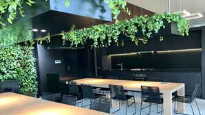 A modern meeting room with two large tables, black chairs, and a wall-mounted kitchen area. - Melbourne CBD 2BD! - Experience Rose Lane! (Melbourne)