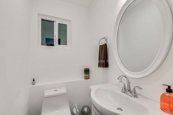 A bathroom with a toilet, sink, and a window.
