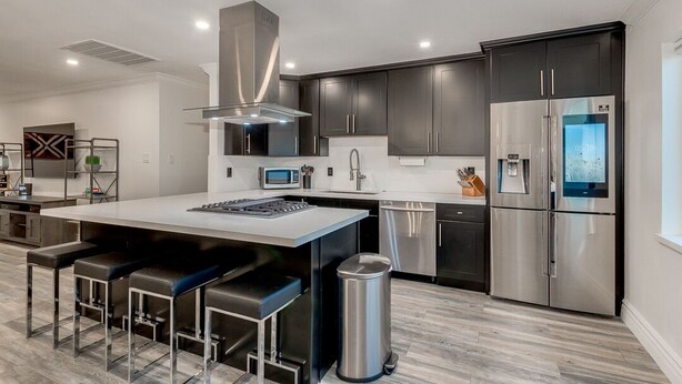 A modern kitchen with dark cabinetry, stainless steel appliances, and a central island with bar stools. - OLD TOWN + HOME + HEATED Private POOL + 4 Bed/ 2.5 Bath + NEW Remodel+ Game Room (Scottsdale)