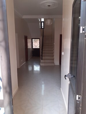 Stunning hallway with a decorative glass door and modern light fixture, leading to a carpeted staircase.