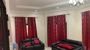 Ein Wohnzimmer mit zwei schwarzen Ledersofas, roten Kissen und roten, gemusterten Vorhängen.