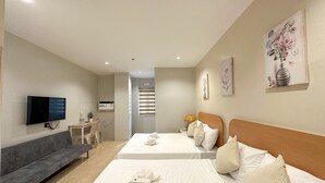 A hotel room with two beds, a sofa, a TV, and a small table with a lamp. - Casa Bicolandia Suites (Daraga)