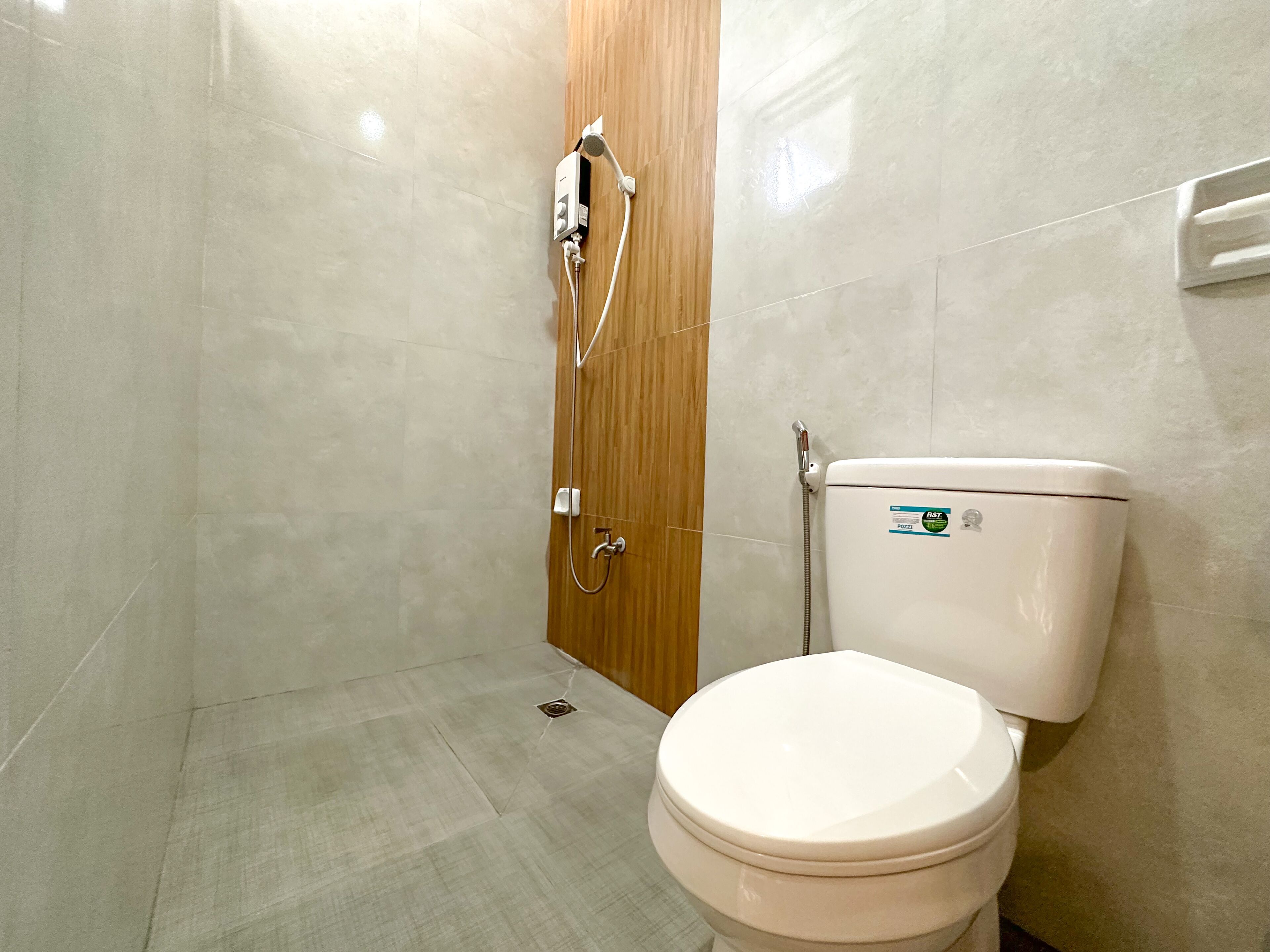 A bathroom with a toilet, a shower, and a wooden door.