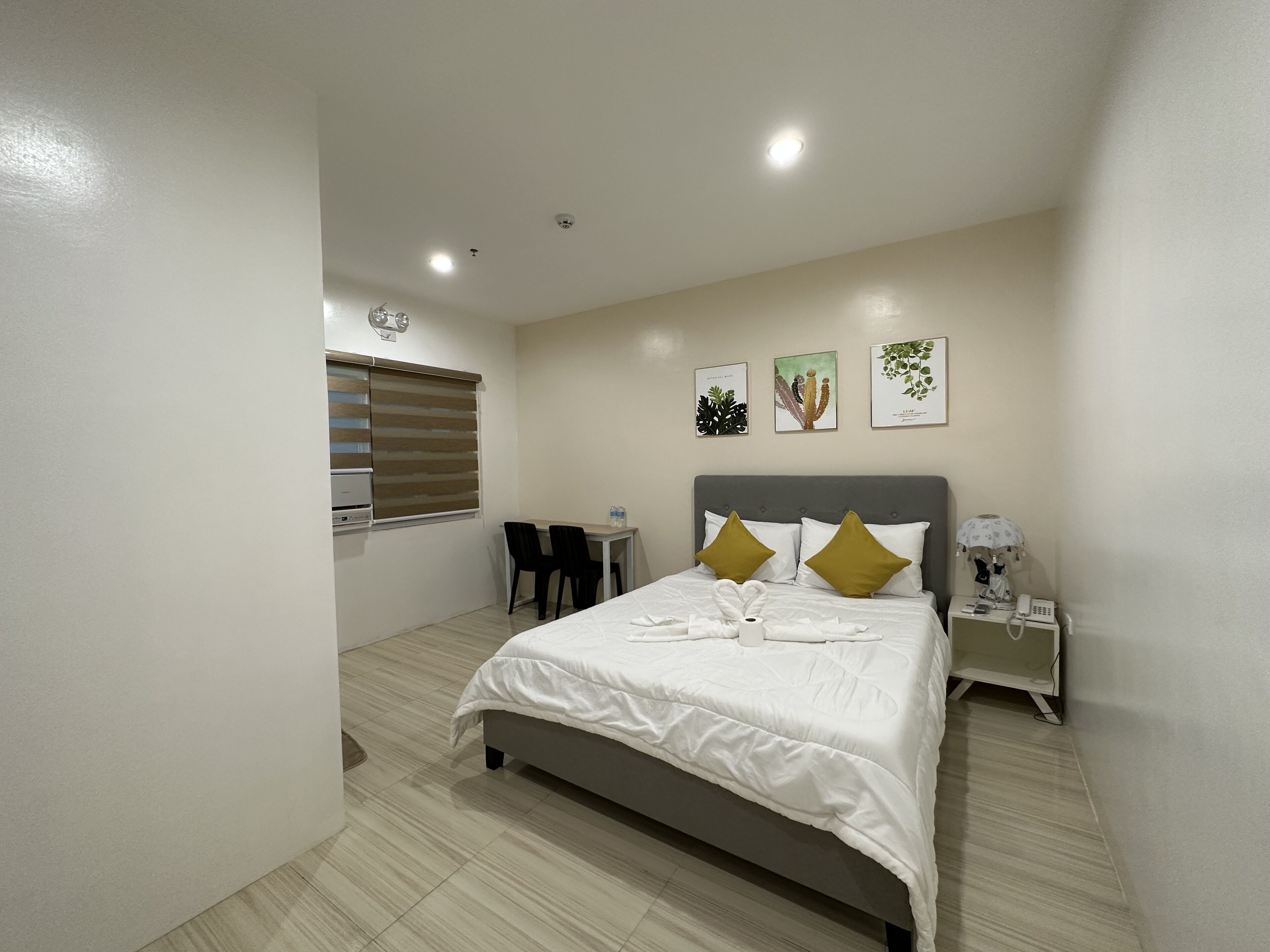 A bedroom with a bed, bedside table, lamp, and a window with blinds.