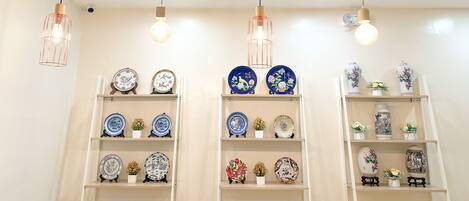 A room with multiple hanging pendant lights and shelves displaying ceramic plates and vases.