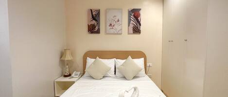 Habitación de hotel con cama, mesita de noche con lámpara y teléfono, y una obra de arte en la pared.