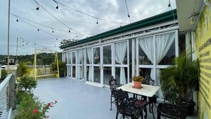 An outdoor patio with a table and chairs, surrounded by potted plants and a yellow railing. - Casa Bicolandia Suites (Daraga)
