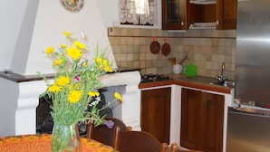A kitchen with wooden cabinets, a stove, and a sink. There is a vase with yellow flowers on the table.