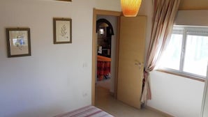 A bedroom with a bed, a wardrobe, a door leading to a bathroom, and a window with curtains.