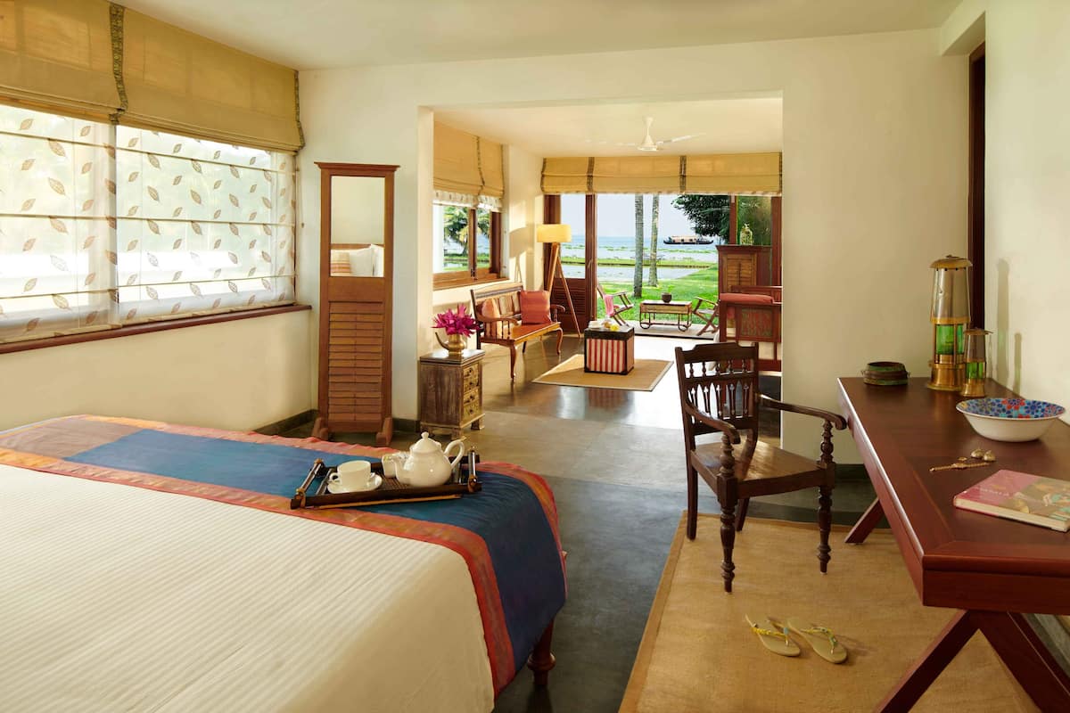A hotel room with a bed, a desk, a chair, a table, and a view of the outdoors.
