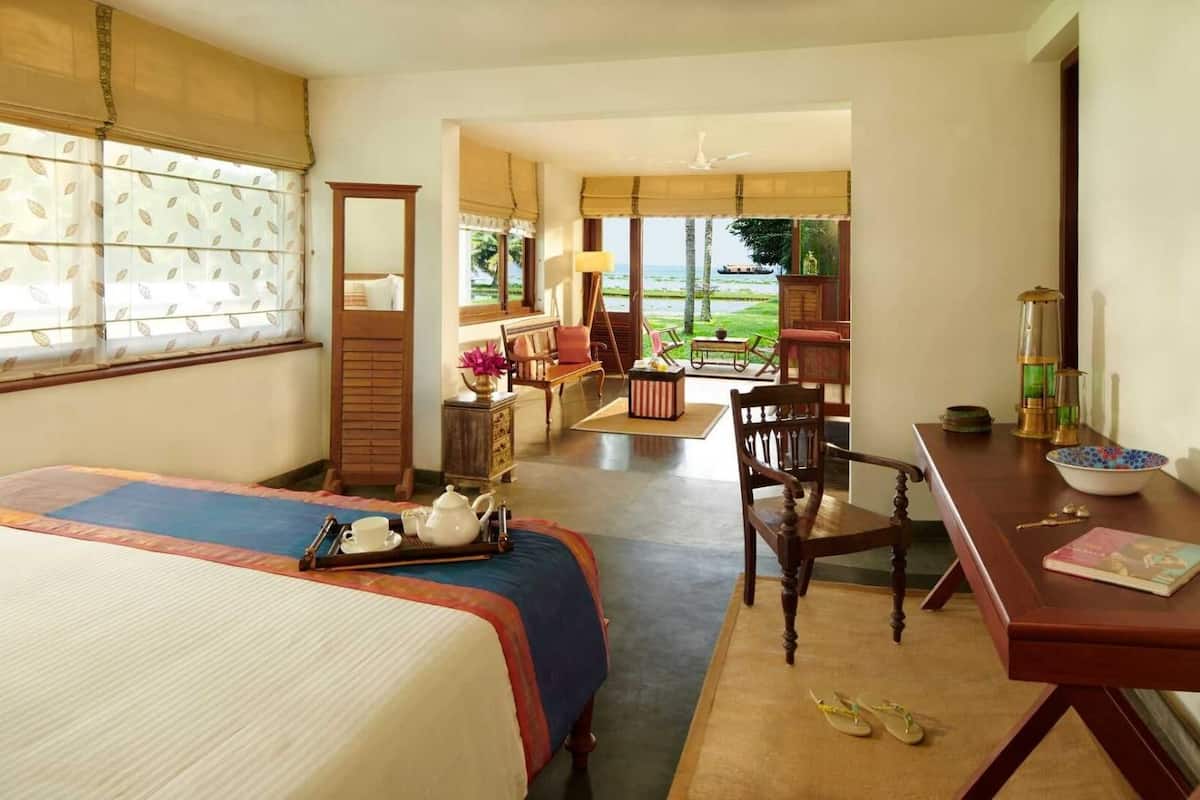 A hotel room with a bed, a desk, a chair, a table, and a view of the outdoors.