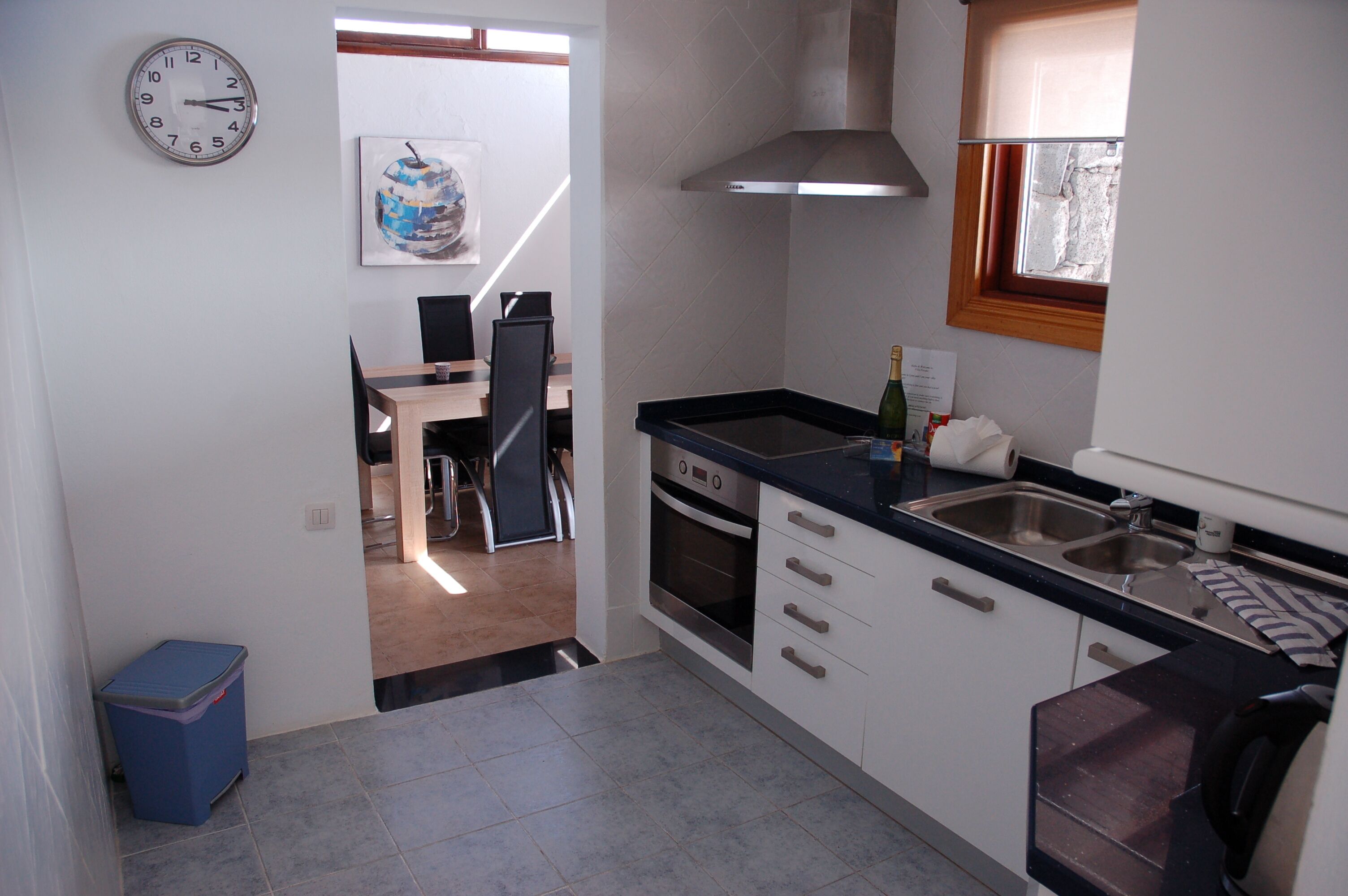 A modern kitchen with a stove, oven, sink, and a clock on the wall.