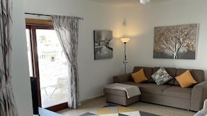 Ein modernes Wohnzimmer mit einer Couch, einem Couchtisch, einer Stehlampe und einem Bild an der Wand.