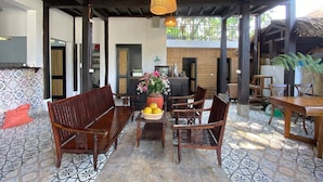 A covered outdoor seating area with wooden furniture and a tiled floor. - Mai Chau Rustic Home - Hostel (Mai Ha)