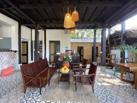 Un espacio de estar al aire libre cubierto con muebles de madera y piso de baldosas.