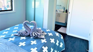A bedroom with a bed, a wardrobe, and a bathroom visible through an open door.