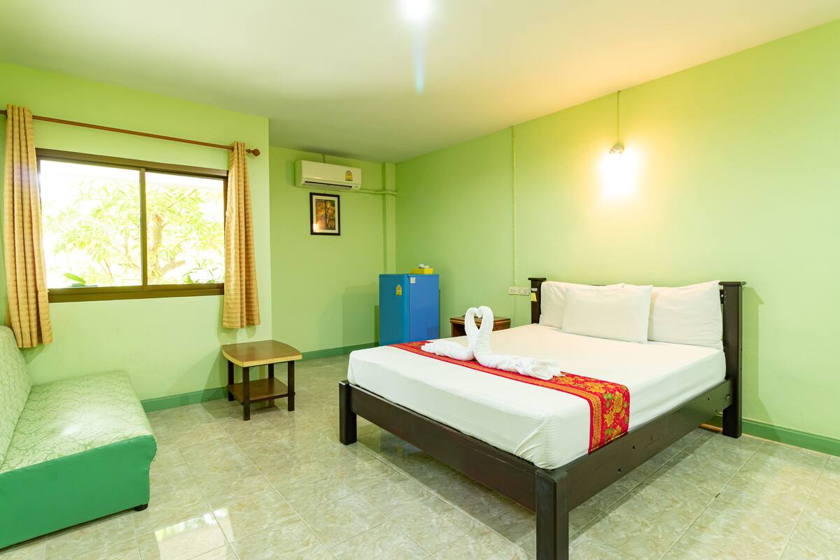 A hotel room with a bed, a sofa, a small table, and a window with curtains.