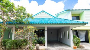 A two-story house with a blue tiled roof, a covered porch, and a garden with various plants and a large vase. - Khum Suk Resort (Hat Yai)