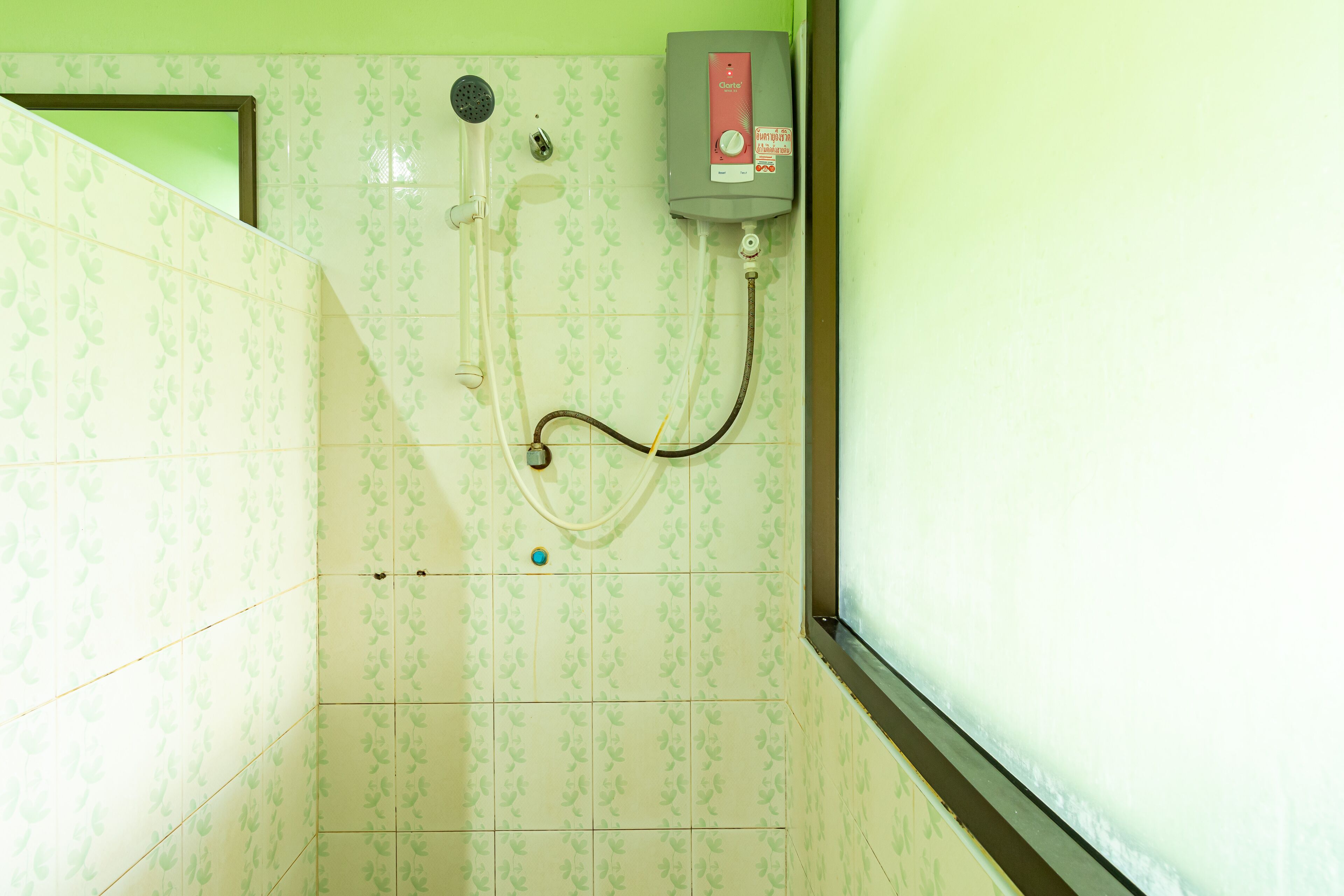 A bathroom with a shower, a water heater, and tiled walls.
