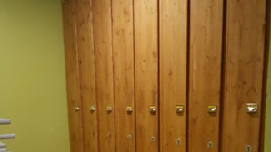 Een rij houten kastjes met metalen sluitingen tegen een groene wand.