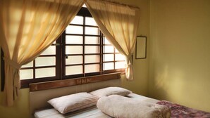 A room with a bed, a window with curtains, and a wall-mounted picture frame. - VILLA ADE - 0620 KOTA BUNGA PUNCAK (Cipanas)
