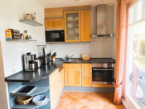 Una cocina con armarios de madera, encimera negra y horno empotrado.