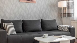 Un salon moderne avec un canapé gris, une table basse blanche et un coussin décoratif à motifs.